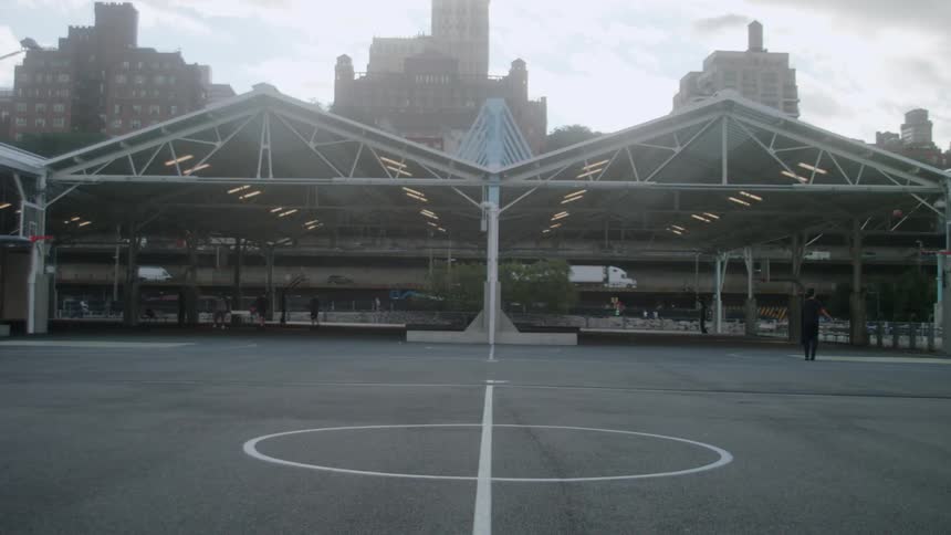 Vehicles drive down a street behind a large basketball court