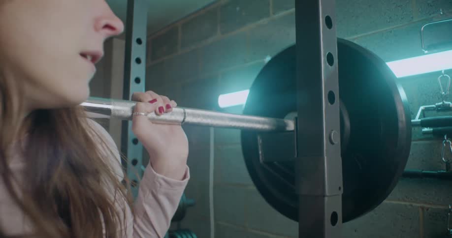 Woman exercises with a barbell in a weight room
