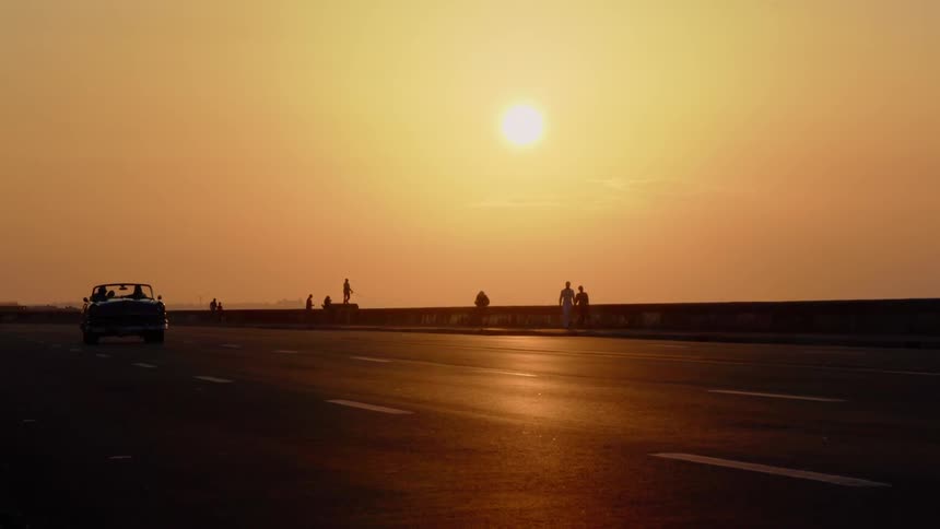 Cars drive on a road at sunset