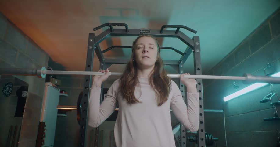 A woman crouches a weight bar in the gym