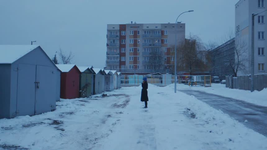 A woman is standing outside on a winter day smoking