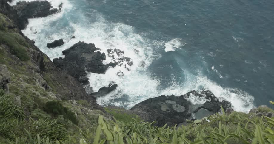 Foamy waves crash into shore near the hills