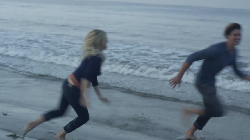Man and woman chasing each other at the beach