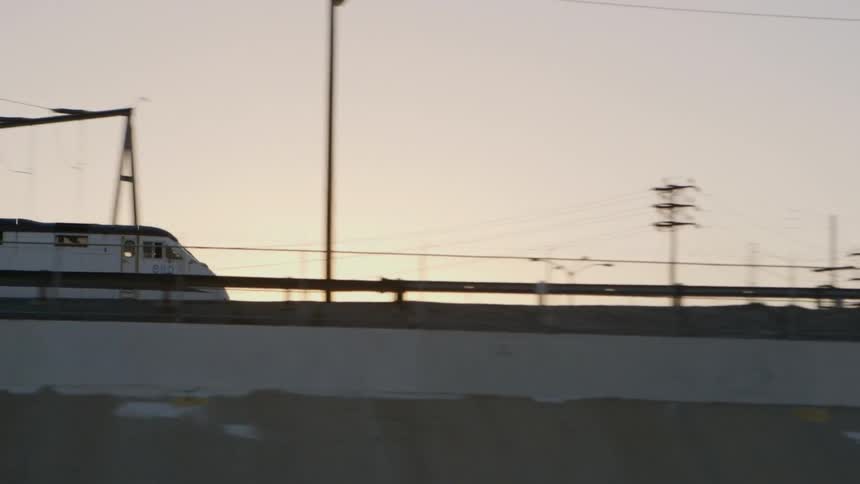 A train passing a bridge at sunset