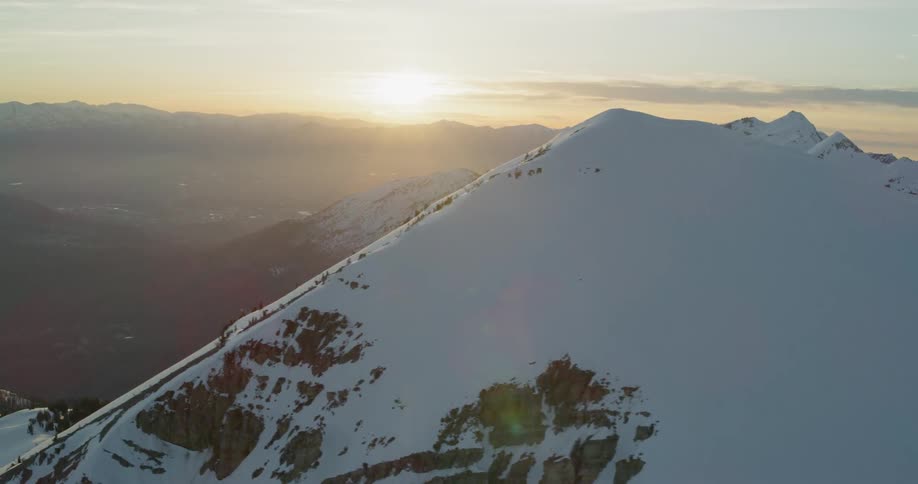 The sun shines on the top of the snowy mountain