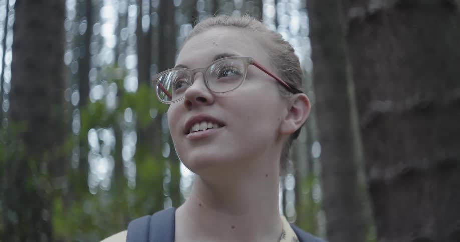 Woman smiles while standing in a forest