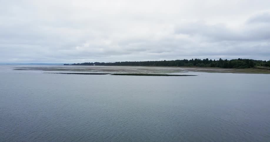 A calm lake sits under a cloudy blue sky
