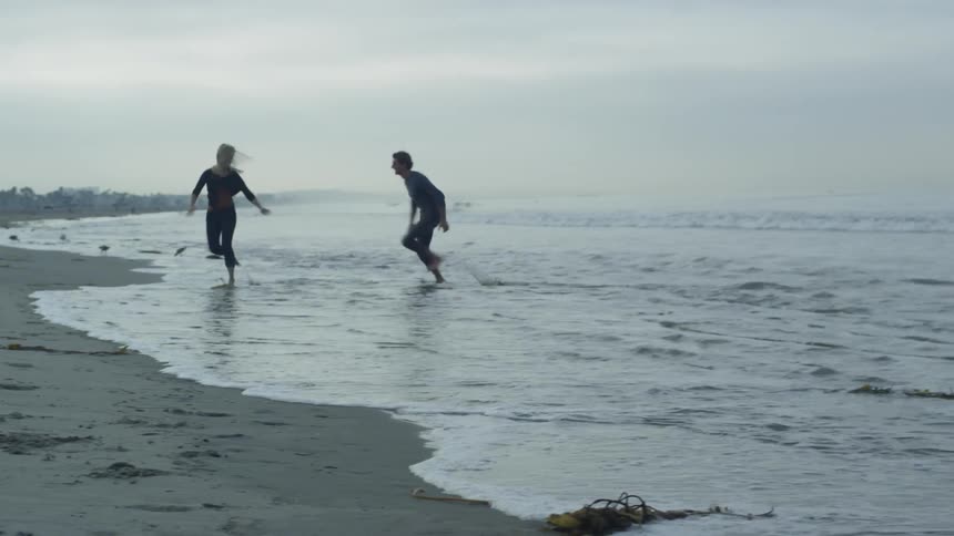 Man and woman play on the beach on a cloudy day