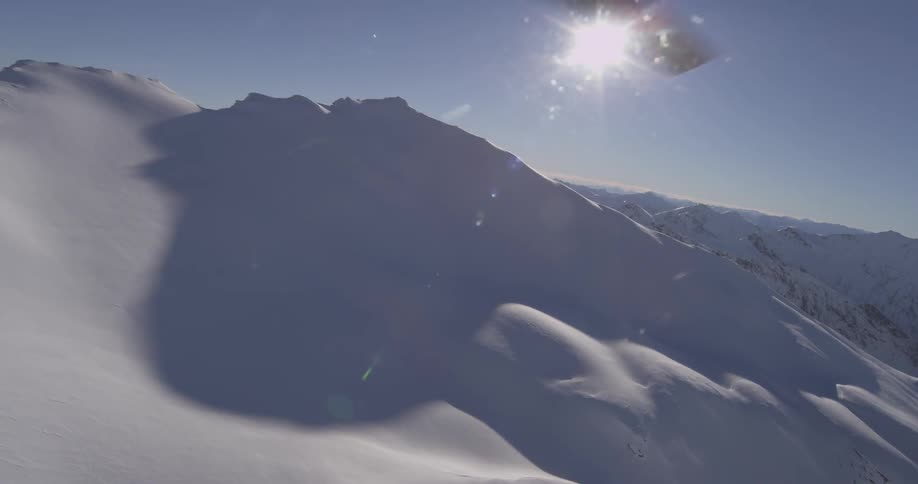 A helicopter is flying over snow covered mountains