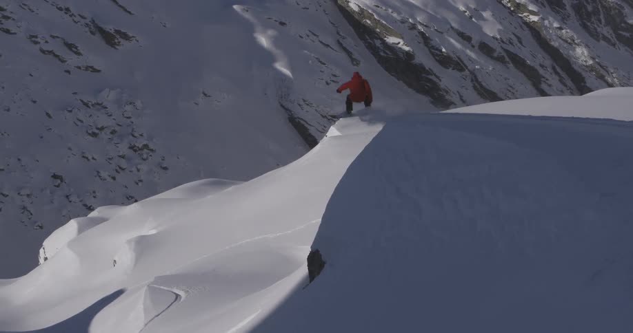 A snowboarder rides down a mountain
