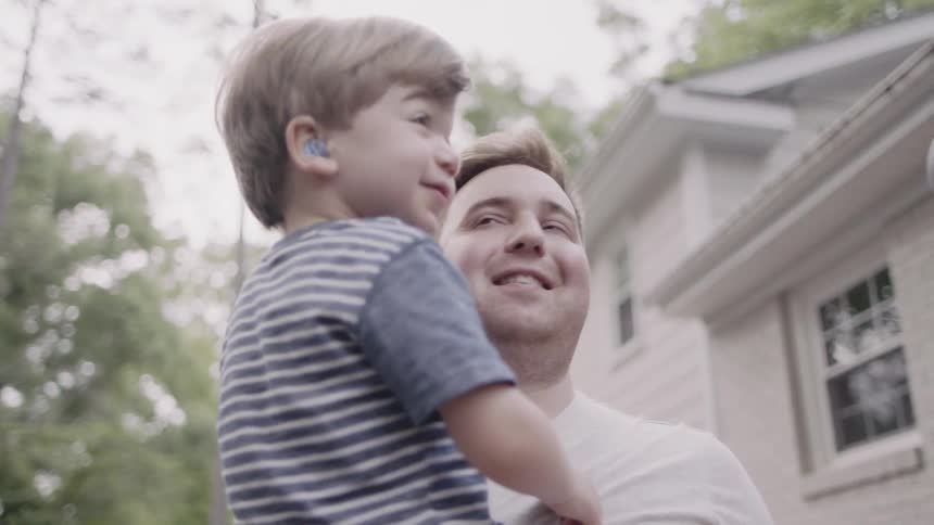 A dad is holding his son outside