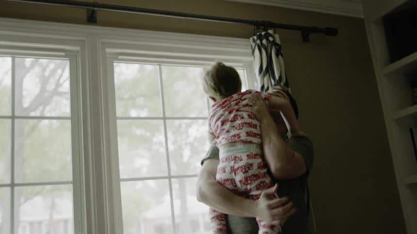 Man lifts and holds a young boy at home