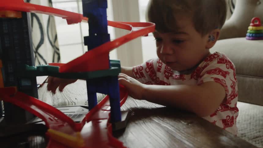 A kid is playing with a car and track set