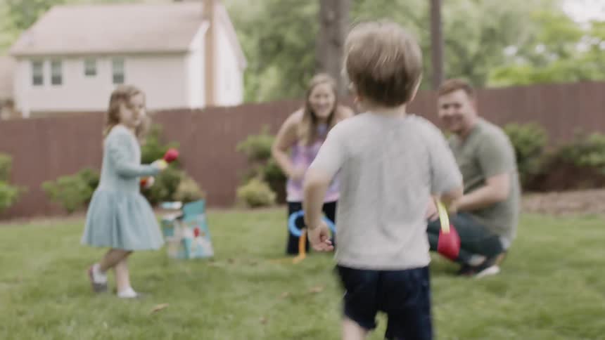 Young boy runs towards a woman as he carries a toy