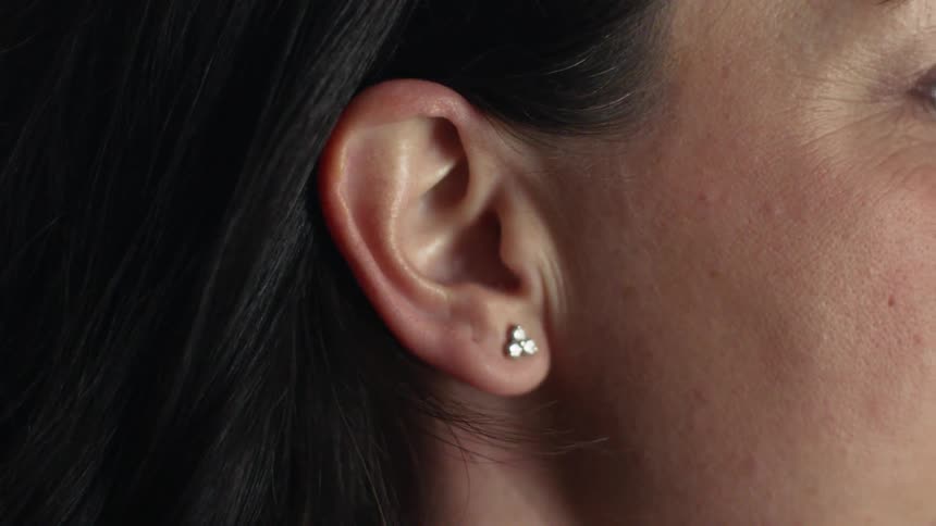 A hand tucks a woman's hair behind her ear