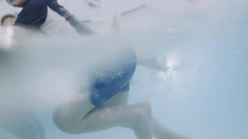A young boy swims in a pool