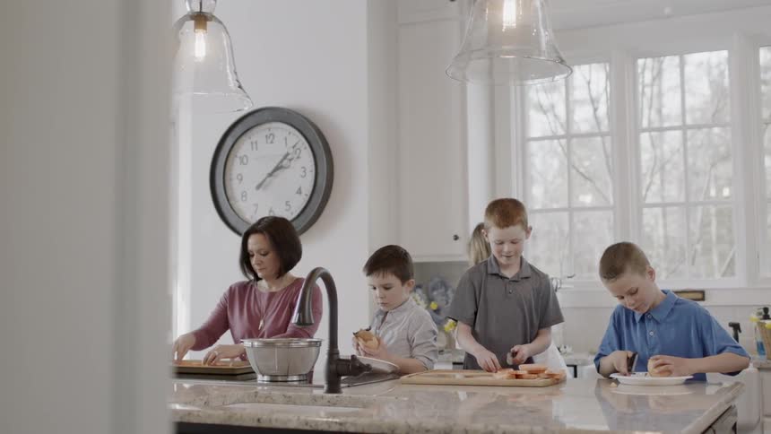 A family cuts vegetables in a home kitchen