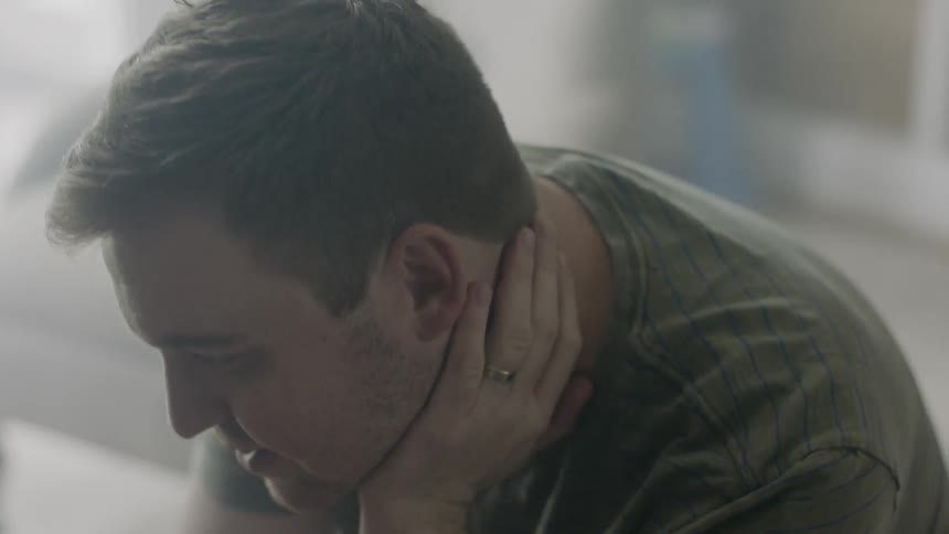 Man talks and rests his hand on his neck