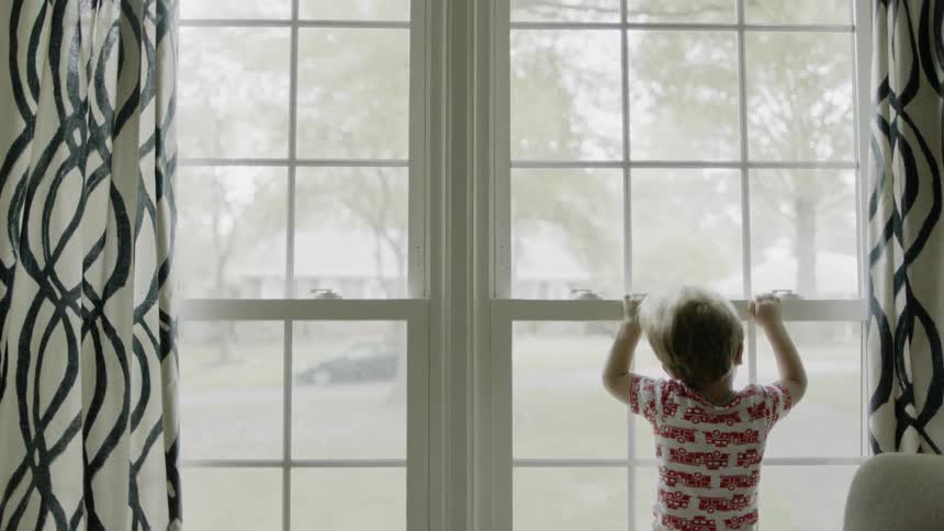 A kid is looking out the window
