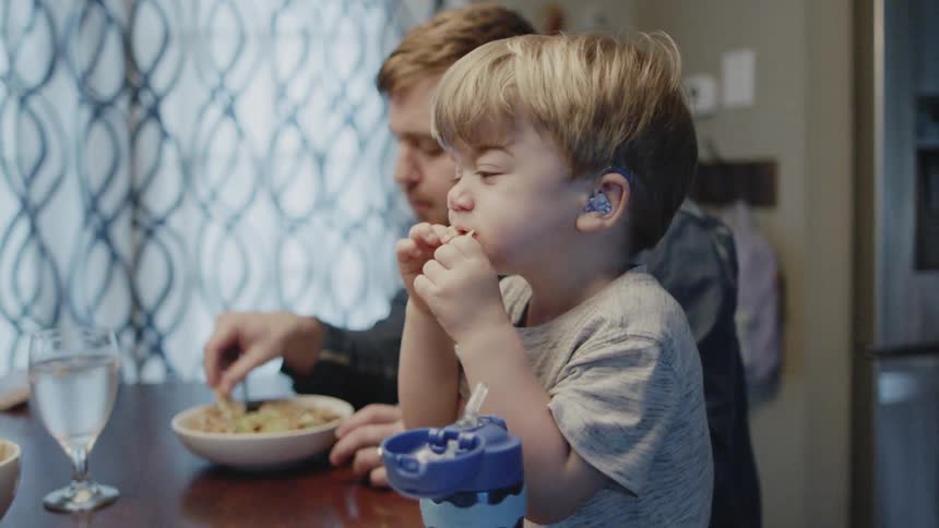 Man and young boy eat at a dining table