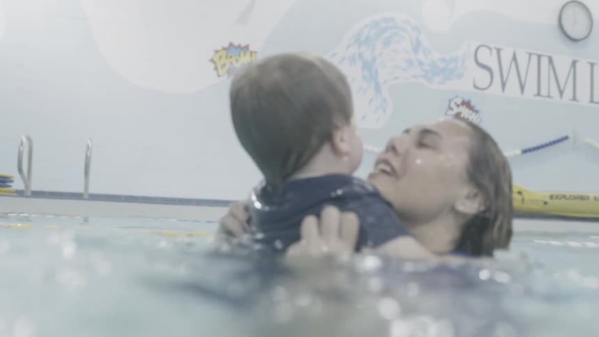 The woman carries the child in the water then they high five