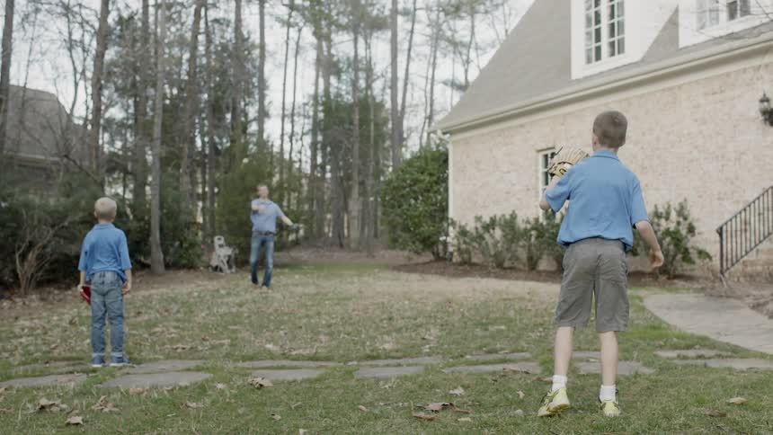 Man and boys play ball in a yard
