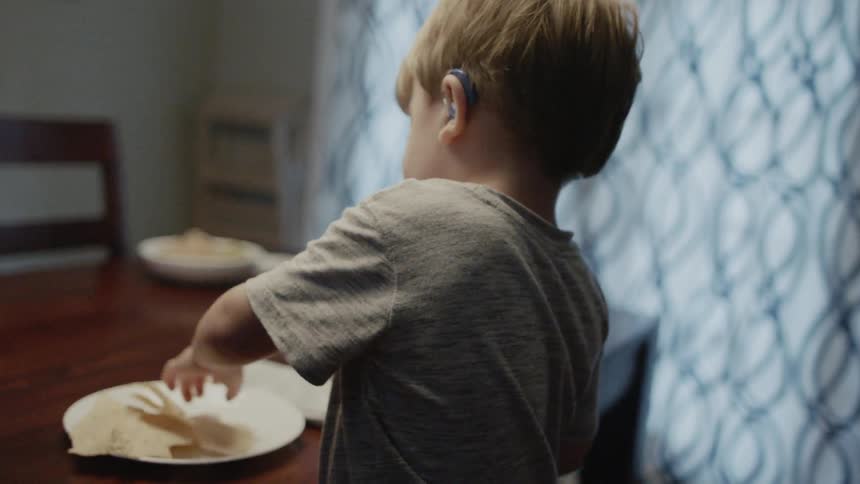 Young boy eats chips at a dining table