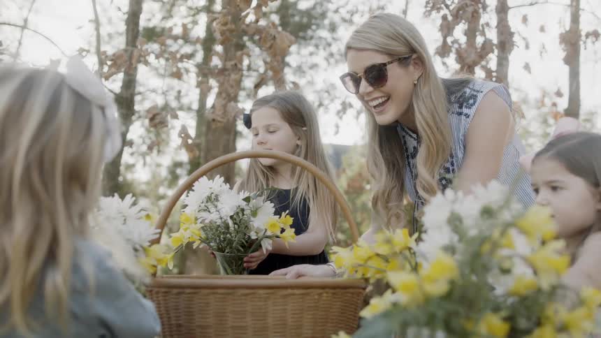Woman and two girls gather flowers outside on a sunny day