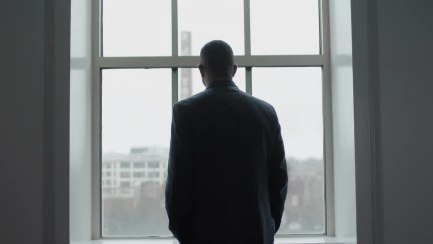 Man wearing a suit looks out a window