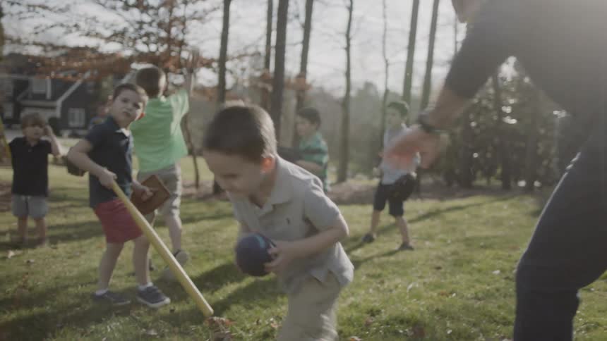 Man and boys play ball in a yard