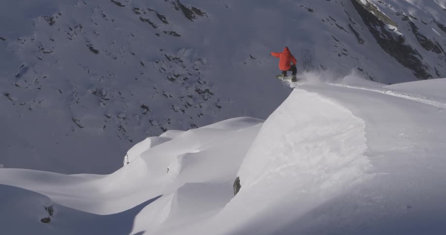 A snowboarder is snowboarding down a mountain