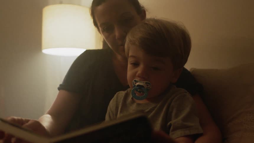 A mother reads a book with a child in her lap