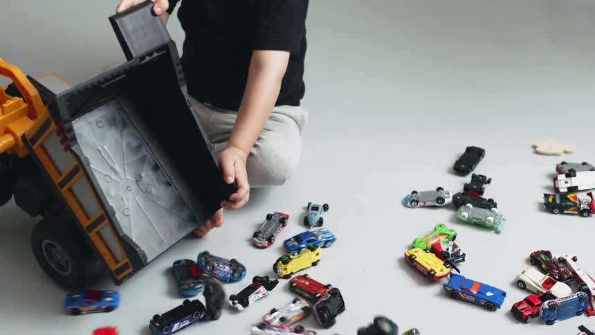 Boy plays with toy cars and a dump truck