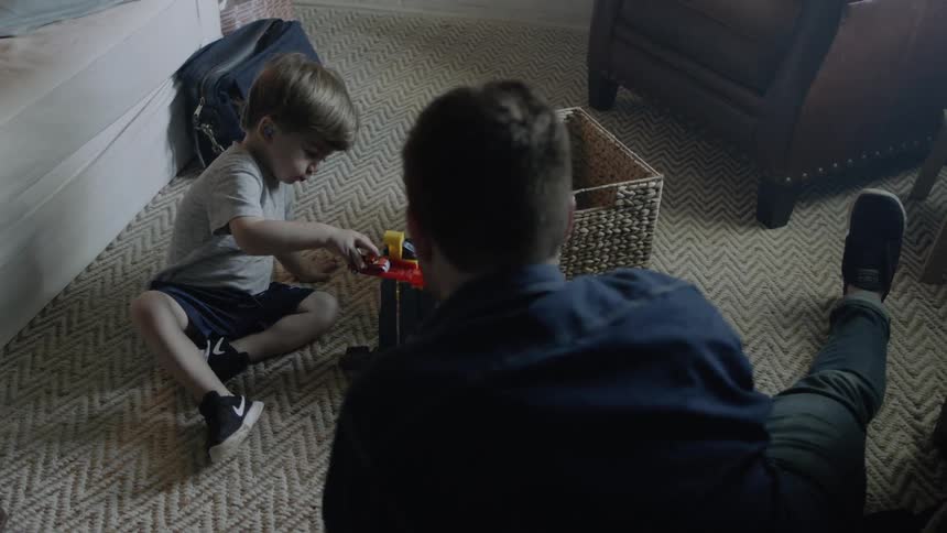 A man and young boy play with toys on the floor