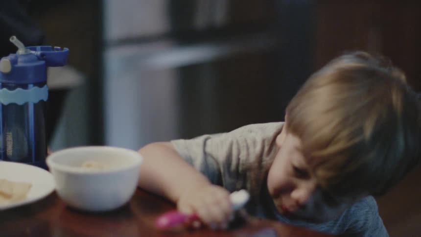 Young boy licks a spoon as he approaches a table