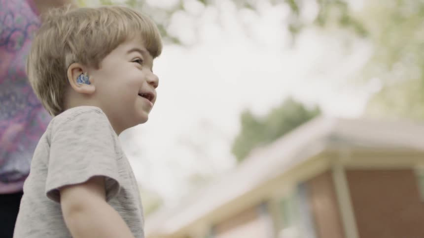 Smiling toddler plays in a yard