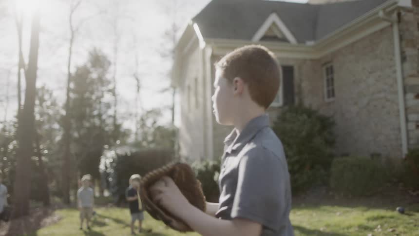 Boys play catch in the yard on a sunny day
