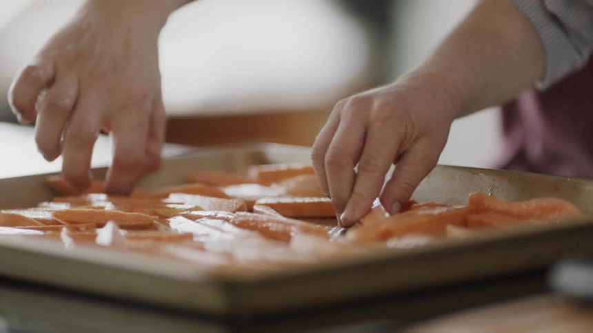 Hands move the french fries on a tray