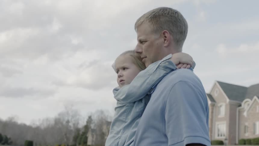 Man carries a young girl in a neighborhood