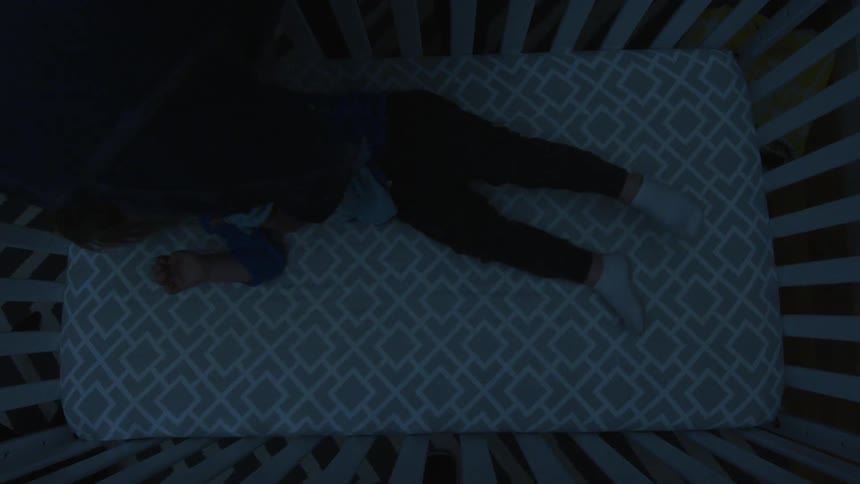 A baby is lifted from a crib