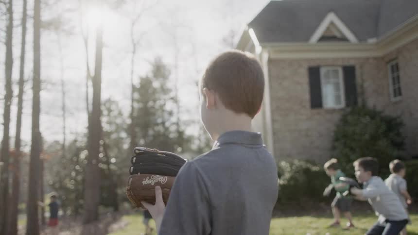 Young boy wears a glove as another boy tosses a ball at him