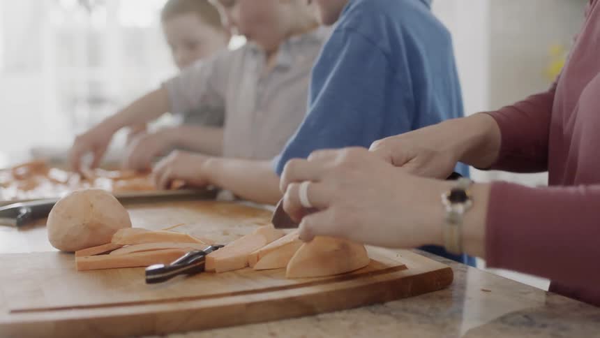 Woman cooks with several children