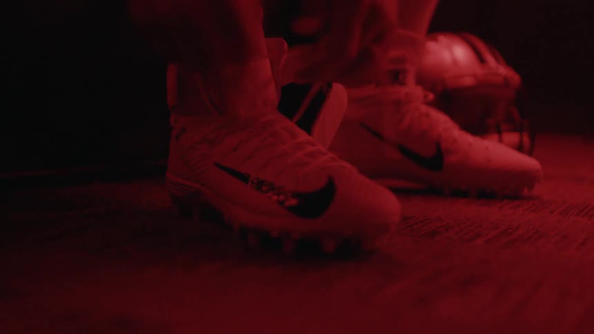 A person ties their sneakers in a dark room