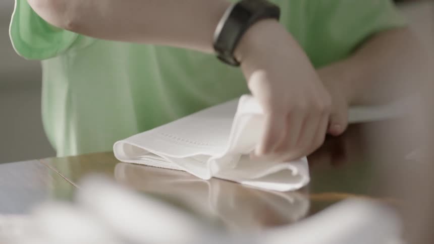 Someone is folding a white napkin on a table