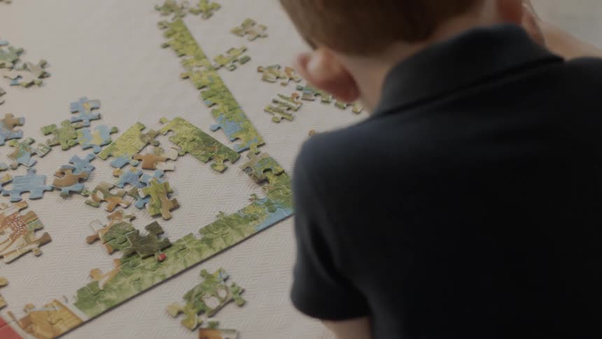Children are sitting at table and putting together a puzzle
