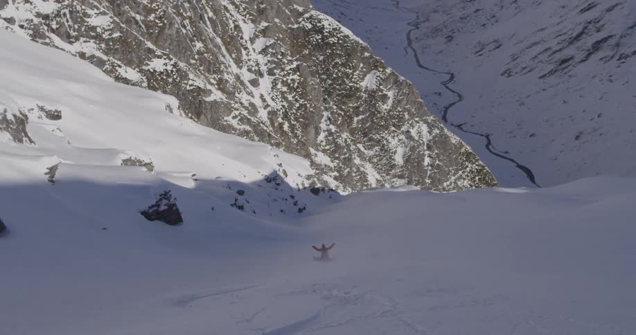 Man snowboarding down a steep snow covered mountain