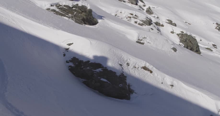 Steep hill covered in snow you can see the shadow of someone climbing up