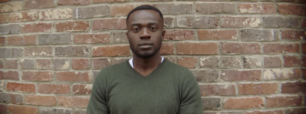 Man leans against a brick wall outside