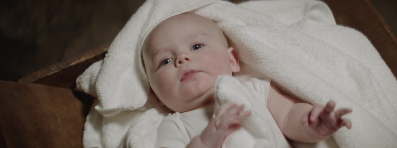 Baby lays on a white towel waving its hand
