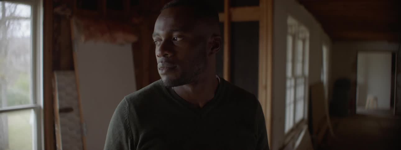 Man stands in a house looking out a window